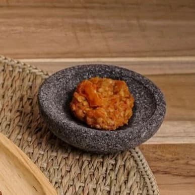 Sambal jokjok berwarna merah oranye di atas cobek batu