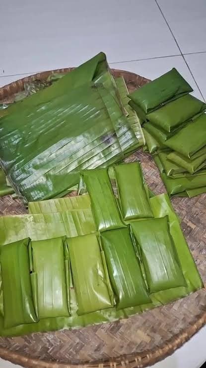 Tumpukan tumpi berbungkus daun pisang di atas nyiru anyaman